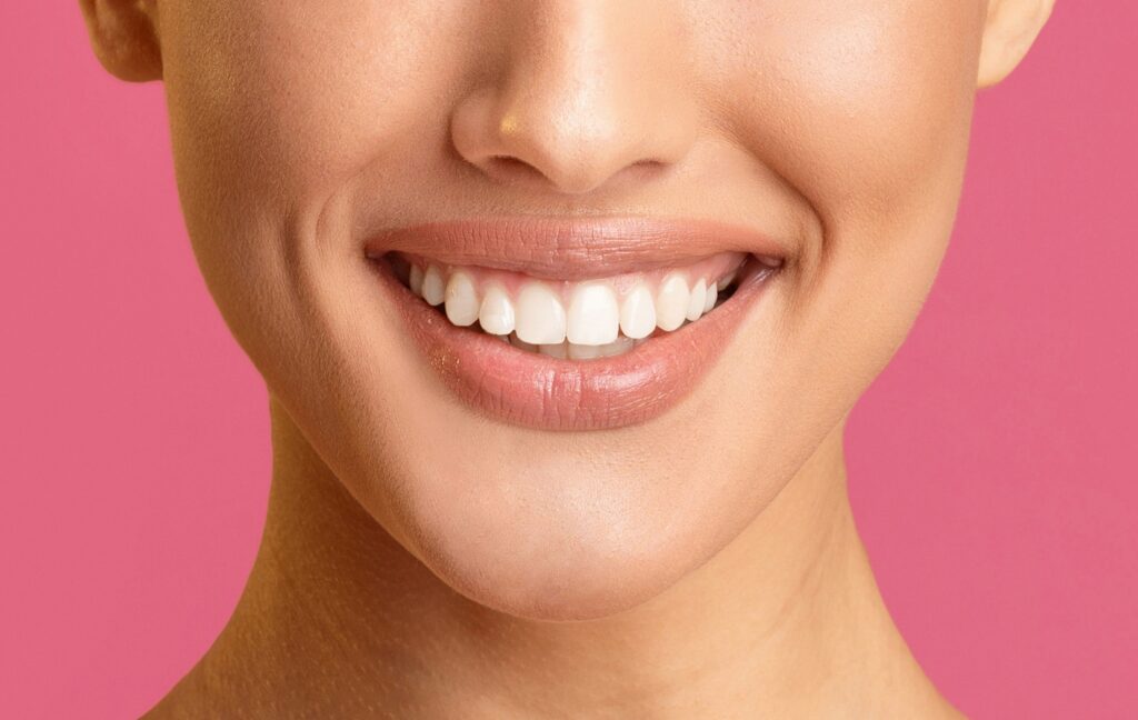 A person smiles brightly to show of their white, straight teeth and their natural-looking dental crown.