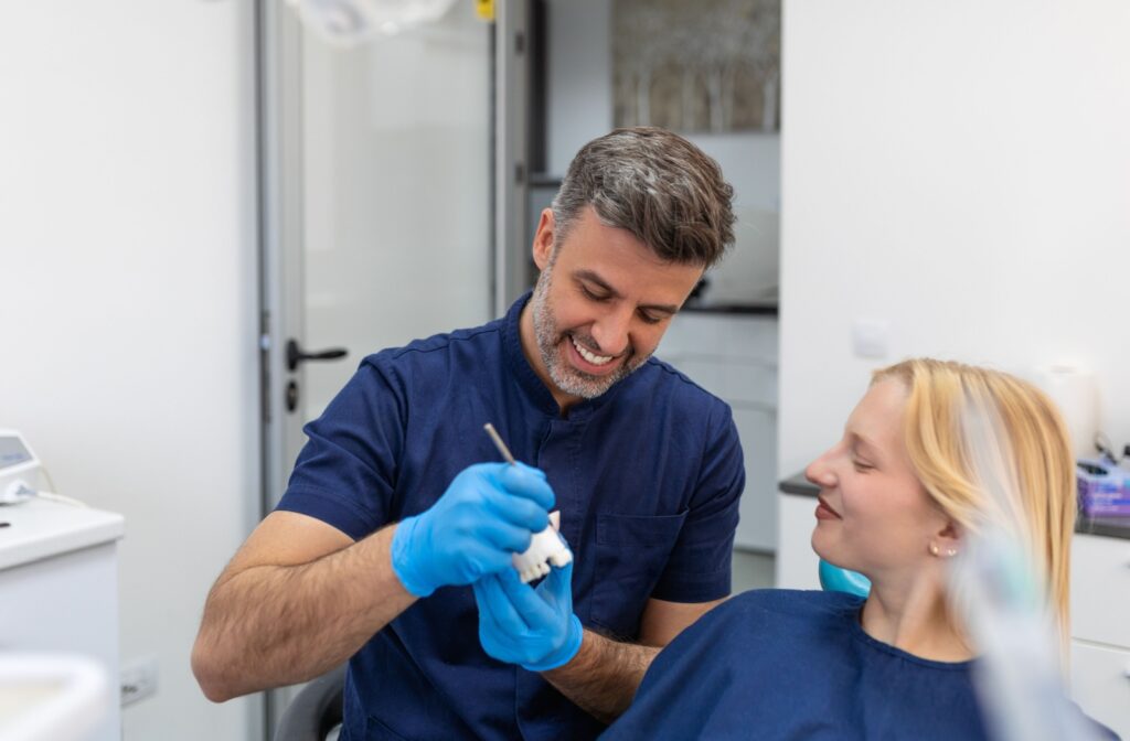 Dentist holding mock veneers up to patient’s teeth to demonstrate potential smile transformation.